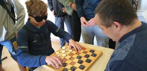 Nuotraukoje - mokinys uždengtomis akimis žaidžia šaškėmis su neregiu G. Stoškumi 