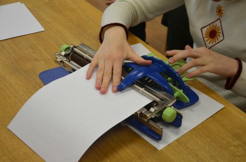 Nuotraukoje - moteris ra&scaron;o brailio ra&scaron;to ma&scaron;inėle, o kita ranka tikrina, ką para&scaron;ė