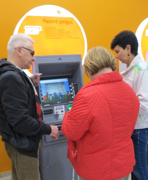 Nuotraukoje - Projekto dalyviai mokosi naudotis kalbančiuoju bankomatu