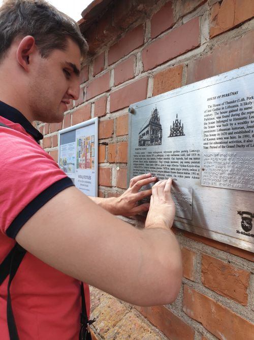 Nuotraukoje - Andžėjus Ravanas tyrinėja rankomis užra&scaron;ą informacinėje lentelėje