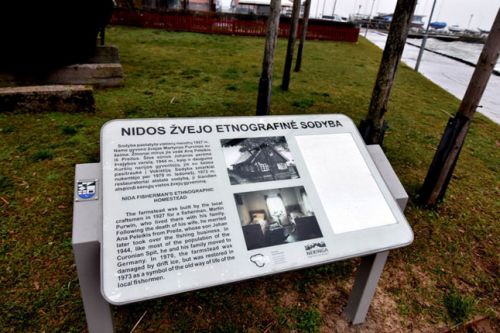 Nuotraukoje - Nidos žvejo etnografinės sodybos informacinis stendas, kuriame yra ir tekstas brailio raštu Nuotraukoje - Nidos žvejo etnografinės sodybos informacinis stendas, kuriame yra ir tekstas brailio raštu
