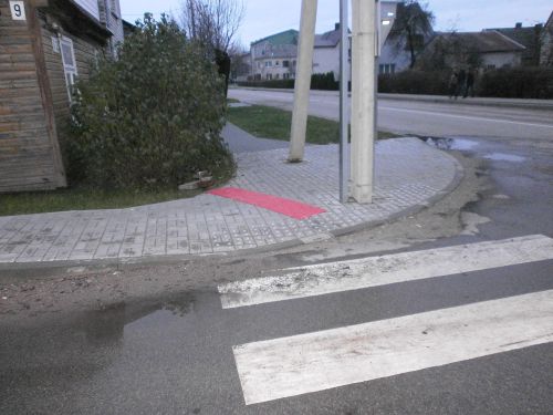 Nuotraukoje - &Scaron;alia pėsčiųjų perėjos, kur yra i&scaron;dėstyta taktilinė danga, bet ap&scaron;vietimo stulpas yra nepaženklintas kontrastingomis spalvomis