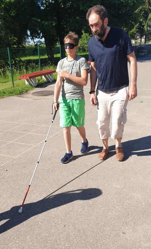 Nuotraukoje - V. Gendvilas moko berniuką vaikščioti naudojant baltąją lazdelę